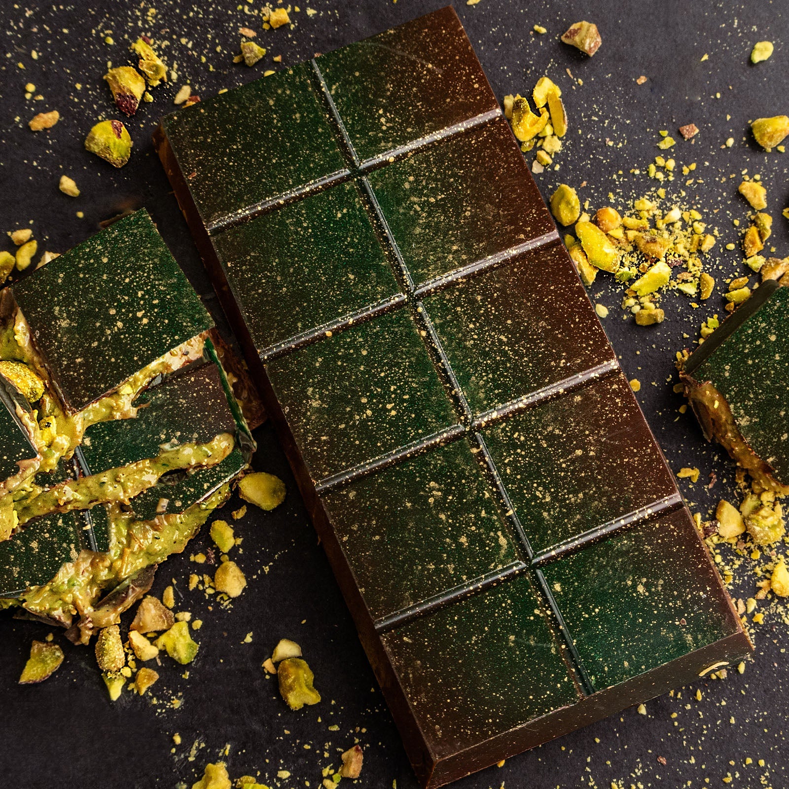Dark chocolate block with pistachio pieces and gold dust sprinkled on top.